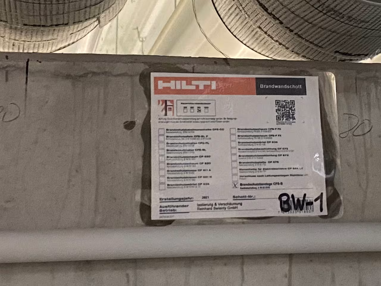 Zertifiziertes Brandwandschott mit Hilti CFS-B Brandschutzbandage und Kennzeichnungs­schild, Ausführung durch IVS Isoliertechnik