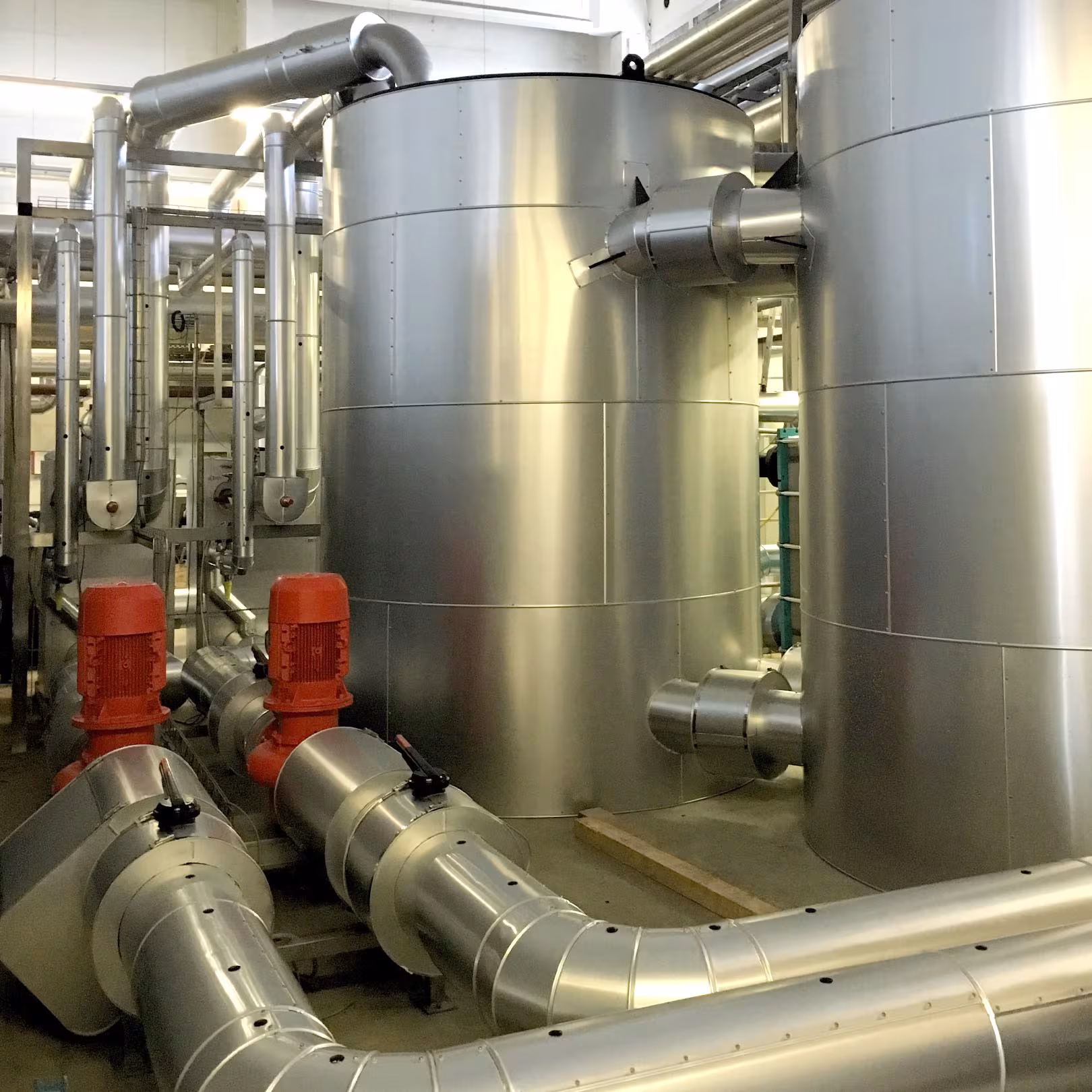 Isolierte Lagertanks mit Edelstahl-Mantel und gedämmte Pumpenleitungen in einer Milchverarbeitungsanlage