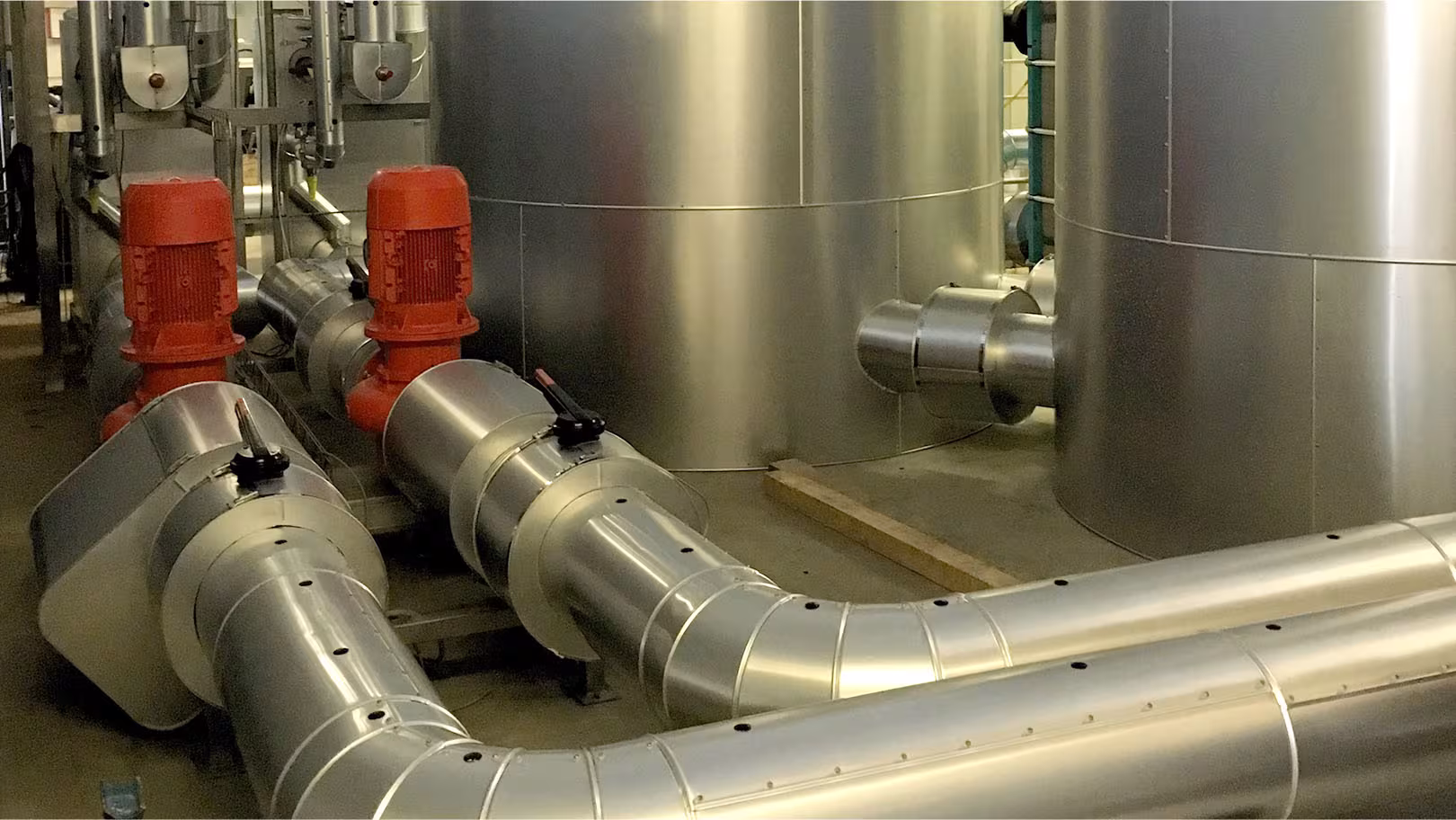 Isolierte Tanks und gedämmte Pumpenanschlüsse mit Edelstahl-Mantel im Abfüllbereich einer Molkerei