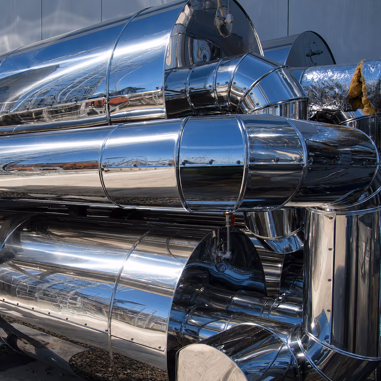 Thermal insulation on shiny stainless steel pipes and technical pipework in an industrial installation